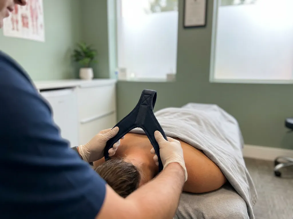 Chiropractor past Y-strap tractietechniek toe op nek en bovenrug van patiënt op behandeltafel in moderne praktijk.
